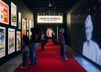 A room with walls covered with a large photo of Marilyn Monroe and posters of her movies.