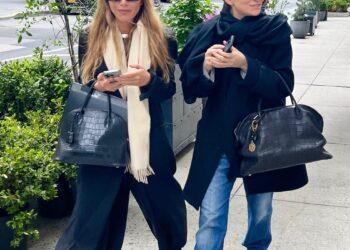 Two individuals walking on a sidewalk surrounded by greenery.