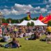 A large crowd at an outdoor summer music festival and fair.