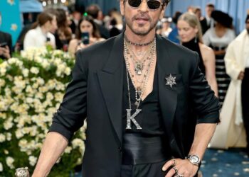 Shah Rukh Khan: Making his Met Gala debut, Shah Rukh Khan channelled dandyism in a sharp all-black Sabyasachi ensemble. A rhinestone-studded “K” pendant, layered jewellery, and a cane brought in a touch of drama, while his tousled hair, dark sunglasses, and leather boots added his unmistakable signature edge. (Image: Instagram)