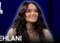 Kehlani on Complex News, smiling with long wavy hair and visible tattoos, against a blue background.