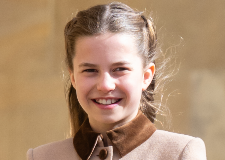 Princess Charlotte wears a light brown coat with a dark collar and smiles