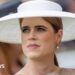Princess Eugenie wearing a large wide-brimmed white hat, gold toadstool earring and brown dress