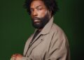 Questlove in front of a green background
