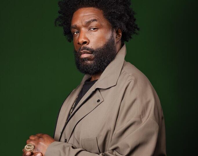 Questlove in front of a green background