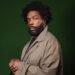 Questlove in front of a green background