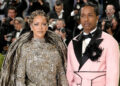 Rihanna in a shimmering gown and ASAP Rocky in a pink suit at the 2026 Met Gala, surrounded by photographers.