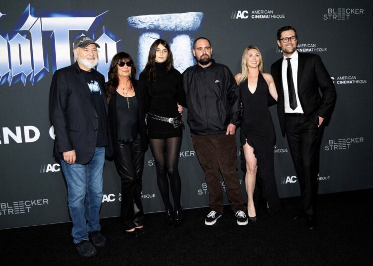 A family of six people dressed largely in black pose outside of a movie premiere.