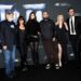A family of six people dressed largely in black pose outside of a movie premiere.