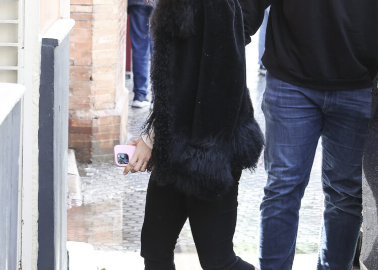 Rosalia in Seville wearing a jacket with a faux-fur trim, black capri pants, and white high-vamp ballet flats