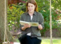 Princess Eugenie reading a book while sitting on a swing