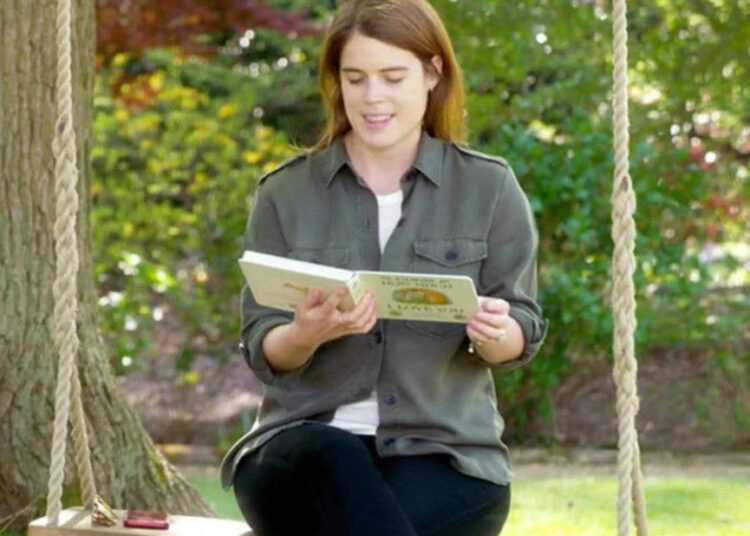 Princess Eugenie reading a book while sitting on a swing