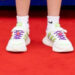 A pair of white trainers on a dazzling red carpet