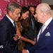 The monarch is dressed in what appears to be a navy blue suit, stood next to his wife, who is wearing a pattered purple dress. They are flanked by award winners who are in dinner jackets