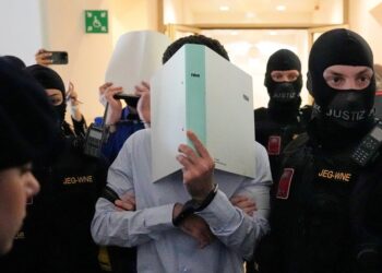 FILE - The defendants hide their faces behind file folders on their way to the courtroom in the District Court in Wiener Neustadt, Austria, where two terror suspects will stand trial Tuesday, one for plotting to carry out an attack on one of superstar singer Taylor Swift's concerts in Vienna in August 2024 and pledging allegiance to the Islamic State group, Tuesday, April 28, 2026. (AP Photo/Matthias Schrader, File)