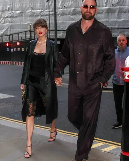 A couple walking hand in hand down a city street during the evening.