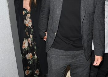 Couple exiting a venue, holding hands.