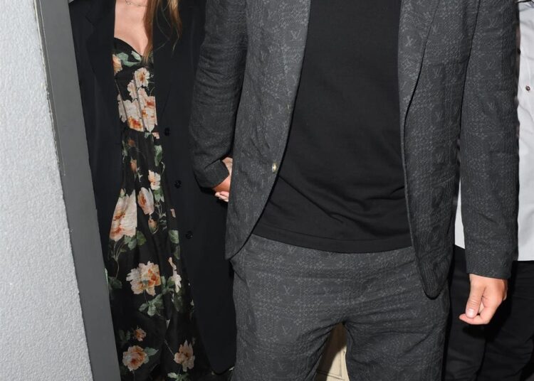 Couple exiting a venue, holding hands.