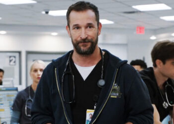Noah Wyle's  Dr. Michael Robinavitch stands in the ER with hsi staff working in the background in The Pitt