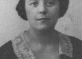 Black and white portrait of a woman with short dark hair, wearing a dark dress with a light lace collar, facing the camera against a plain background.