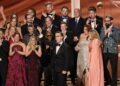 Stephen Colbert, in front of a crowd in formal wear, holds his Emmy statuette.
