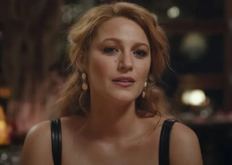 Blake Lively looking forward while wearing a top with black leather straps in It Ends With Us.