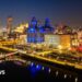 A night city scape of Liverpool lit up in different colours looking out over the docks.