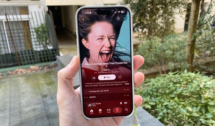 A hand holding an iPhone with Sigrid's latest album on Apple Music being displayed