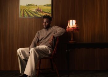 Official album artwork cover for Anendlessocean's Love Is A Machinery featuring the artist sitting on a wooden chair in a wood-panelled room.