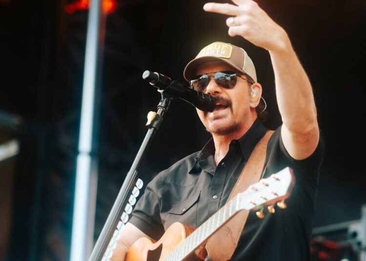 Musician performing on stage with guitar and microphone
