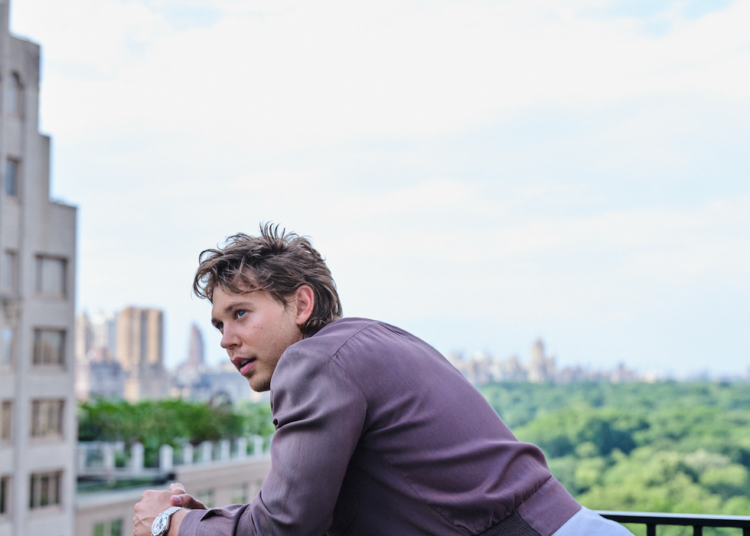 Person leaning on balcony railing with cityscape in background.