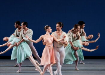 A group of 10 ballerinas perform a dance in formation.