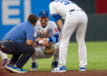 Royals shortstop Bobby Witt Jr., center, talks to manager Matt Quatraro, right, after injuring himself while fielding a ground ball during the fourth inning of a game against the St. Louis Cardinals at Kauffman Stadium in Kansas City on Thursday, June 18, 2026.