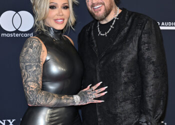 Bunnie Xo, in a black latex dress, and Jelly Roll, in a black suit with face and arm tattoos, pose together at the 68th GRAMMY Awards Pre-GRAMMY Gala.