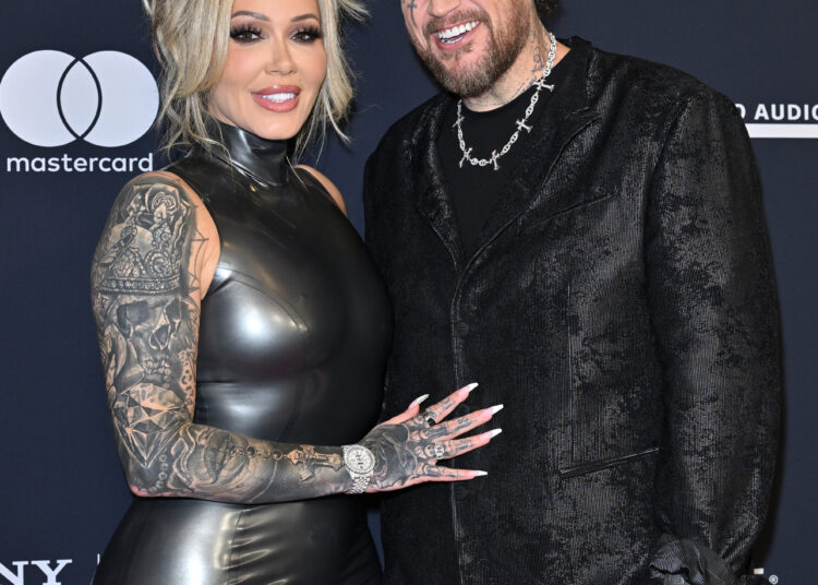 Bunnie Xo, in a black latex dress, and Jelly Roll, in a black suit with face and arm tattoos, pose together at the 68th GRAMMY Awards Pre-GRAMMY Gala.