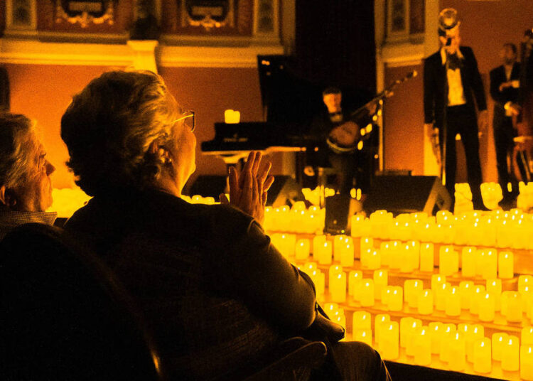 An audience member watches, surrounded by candles at a Candlelight concert.