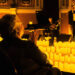 An audience member watches, surrounded by candles at a Candlelight concert.