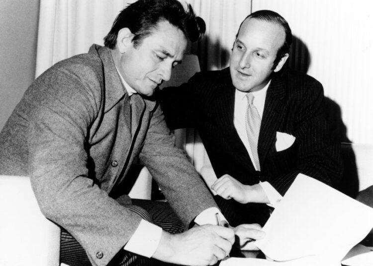 Clive Davis, then a lawyer at Columbia Records, with Johnny Cash as he signs a record contract around 1960, seven years before Davis would become president of the record label.
