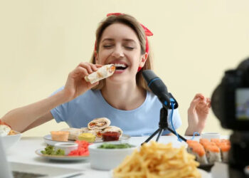 Woman posing with food pretending to eat in front of camera.