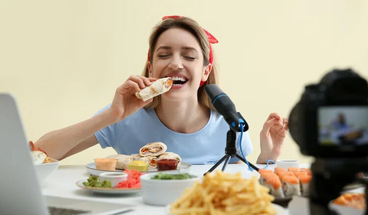 Woman posing with food pretending to eat in front of camera.