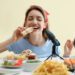 Woman posing with food pretending to eat in front of camera.