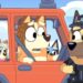 An animated scene features a red car with several dog characters inside. The driver, a tan, and white dog, looks surprised at a police officer dog standing outside the vehicle. The back seat has three smaller dogs wearing flower crowns, reminiscent of Bluey's playful adventures.