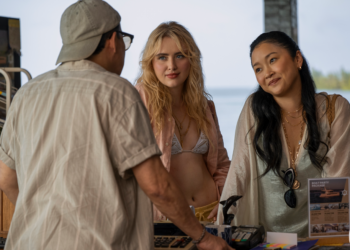 Three people conversing at a counter with ocean in background.