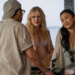 Three people conversing at a counter with ocean in background.