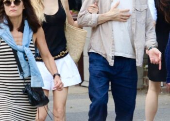 Jason Biggs holding his chest as Jenny Mollen guides him by his arm.
