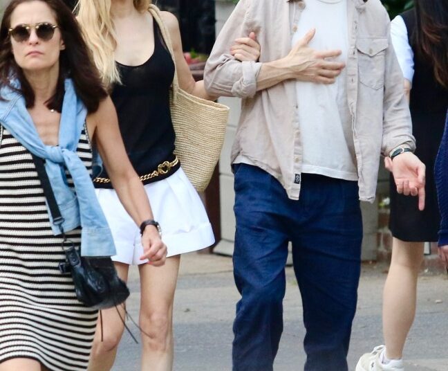 Jason Biggs holding his chest as Jenny Mollen guides him by his arm.