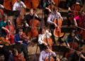 FSU musicians perform on stage during an orchestral concert, with string players seated throughout the ensemble.