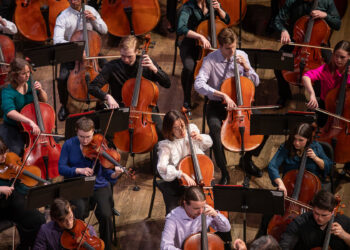 FSU musicians perform on stage during an orchestral concert, with string players seated throughout the ensemble.