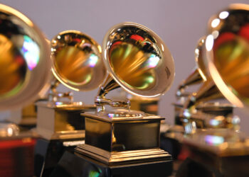 Close-up of multiple Grammy Award trophies, featuring gold gramophones on black bases, arranged in rows.