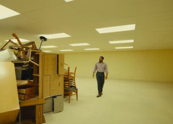 Clark looking at a mess of furniture in Backrooms